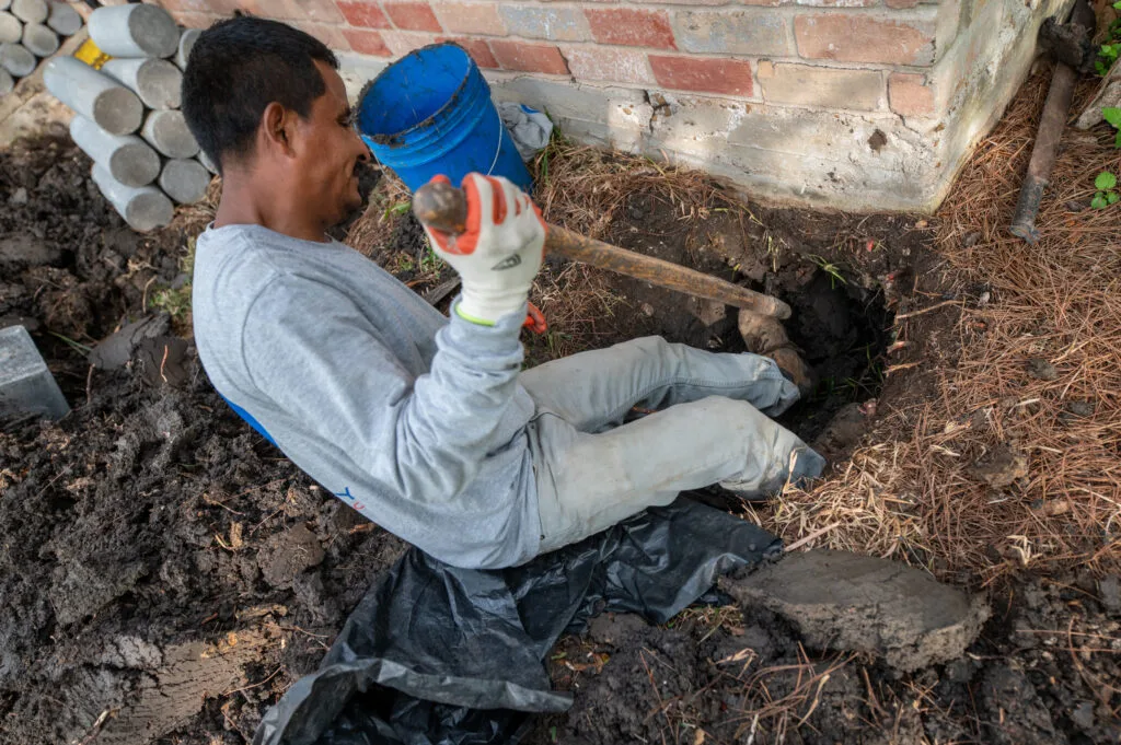 Worker preparing a concrete piling beside a brick wall