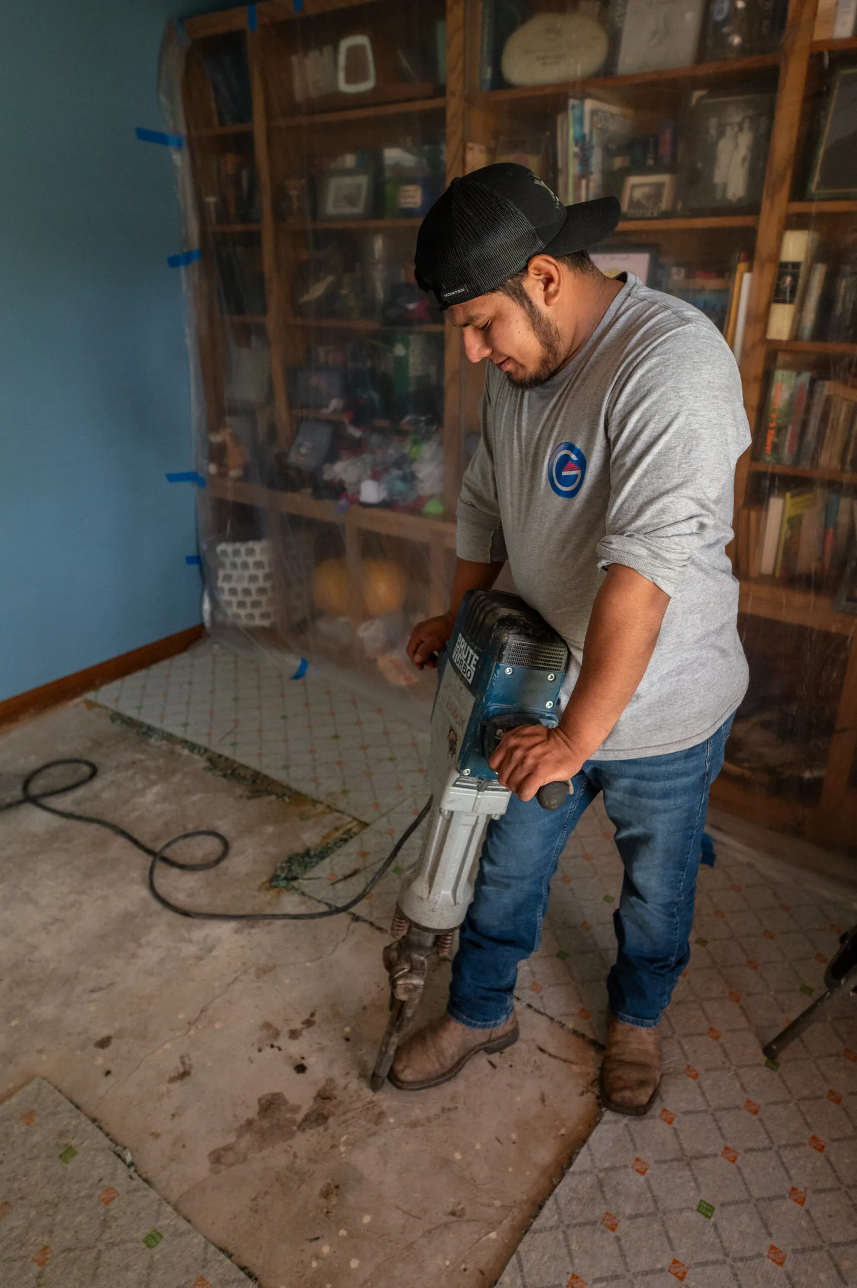 Technician breaking an indoor concrete floor with a jackhammer