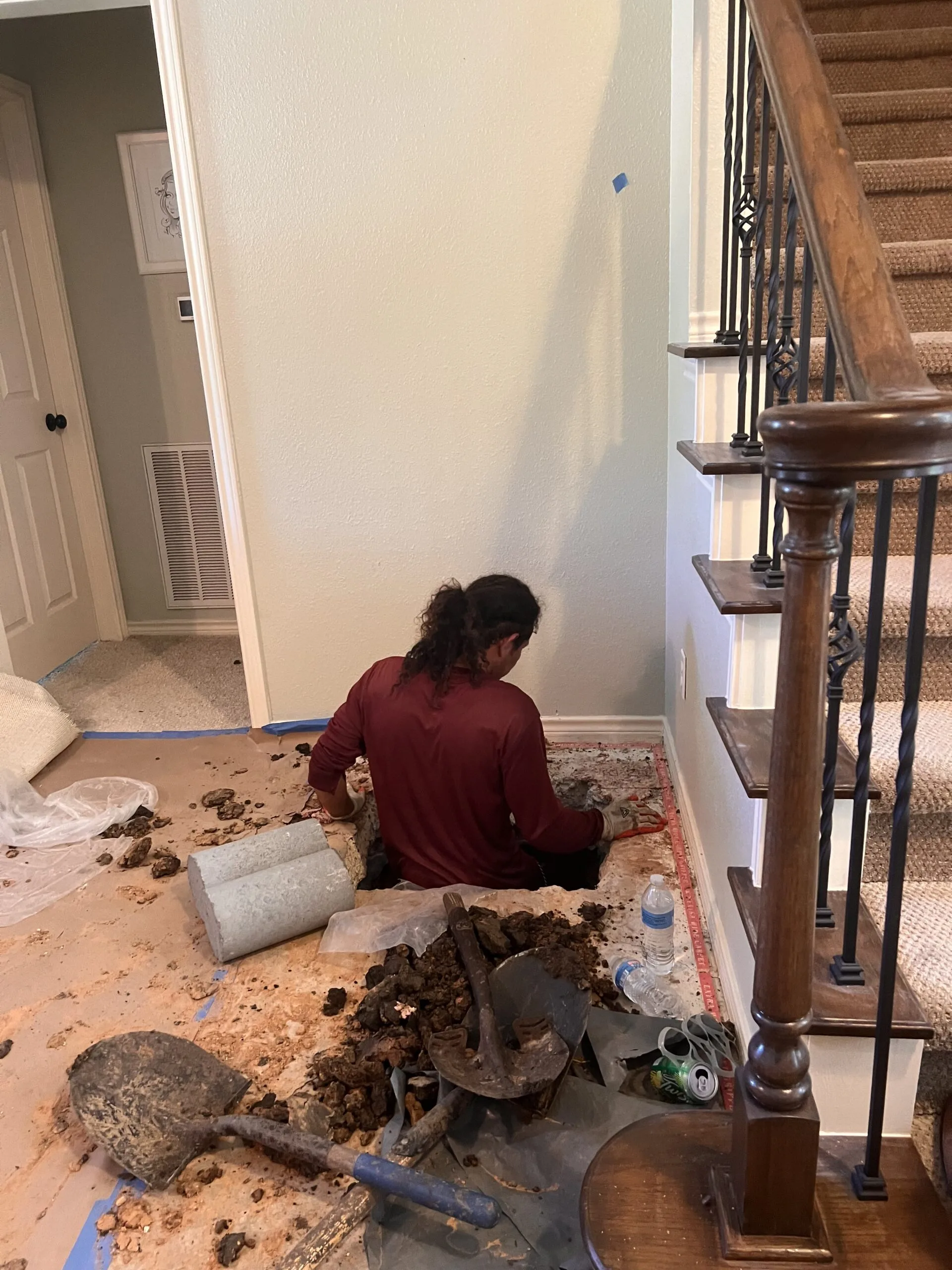 Worker excavating a concrete floor inside a home