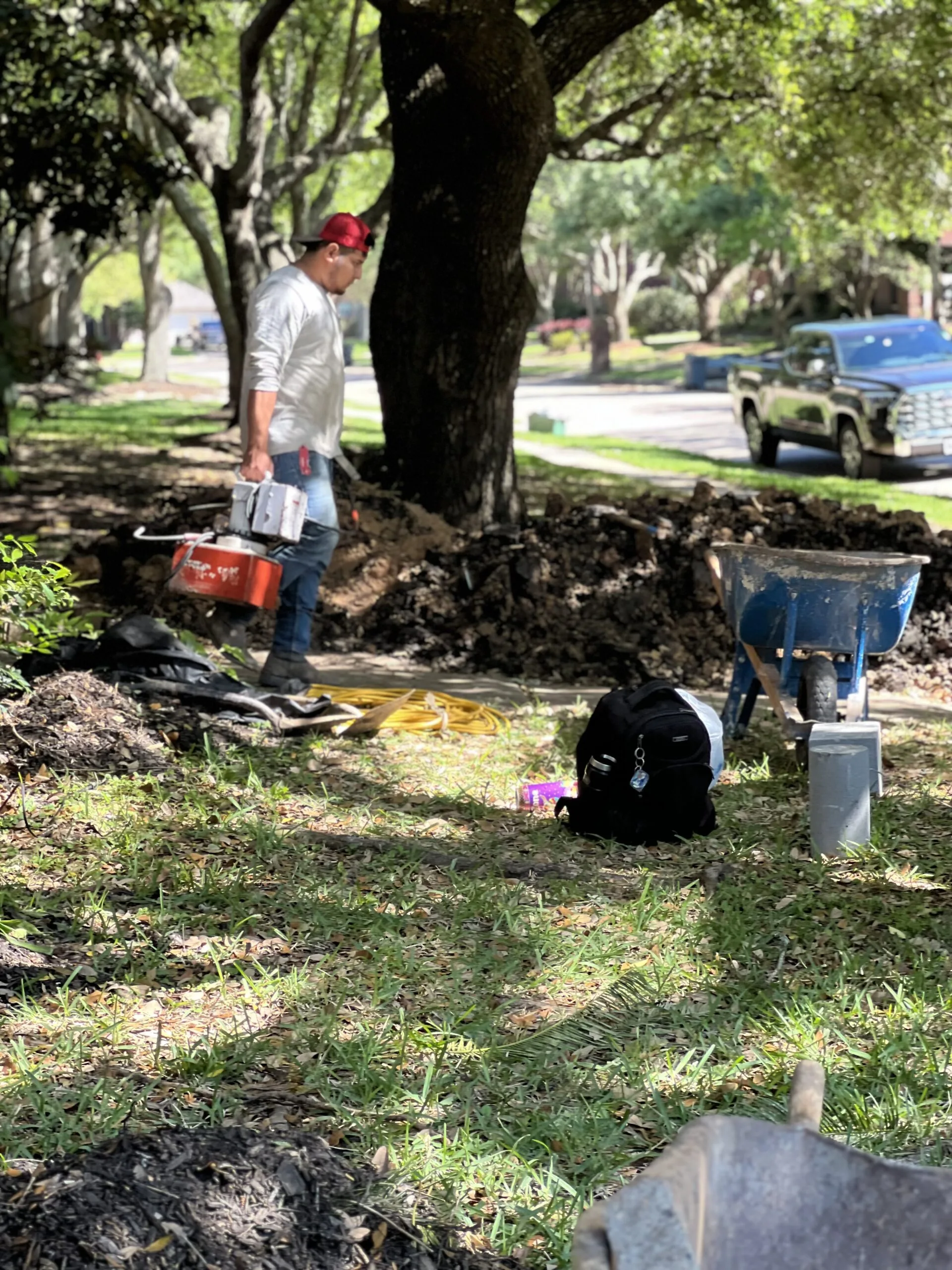 Worker preparing a root barrier trench near a tree