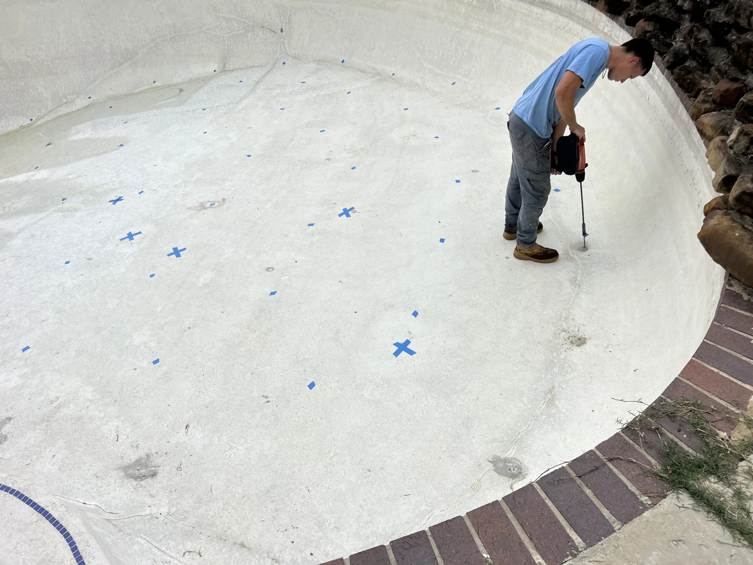 Worker drilling a swimming pool deck for stabilization