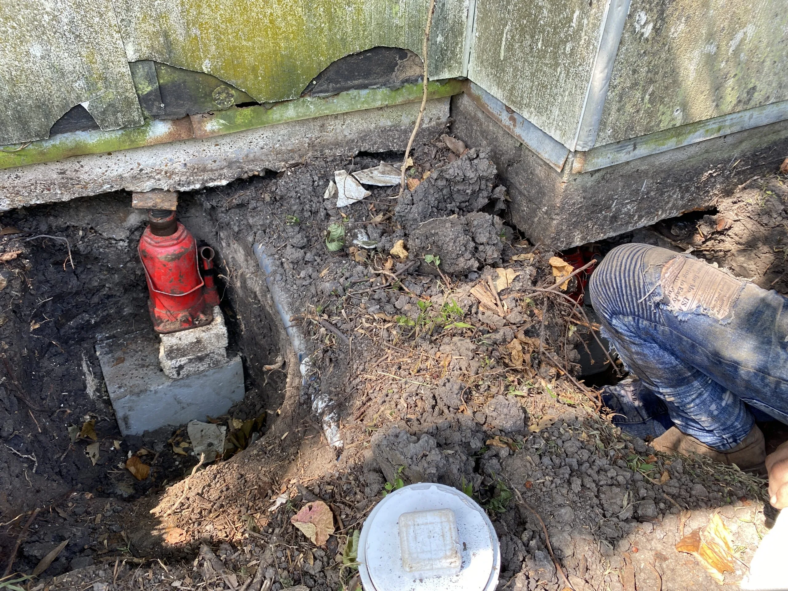 Worker repairing a foundation with a hydraulic jack