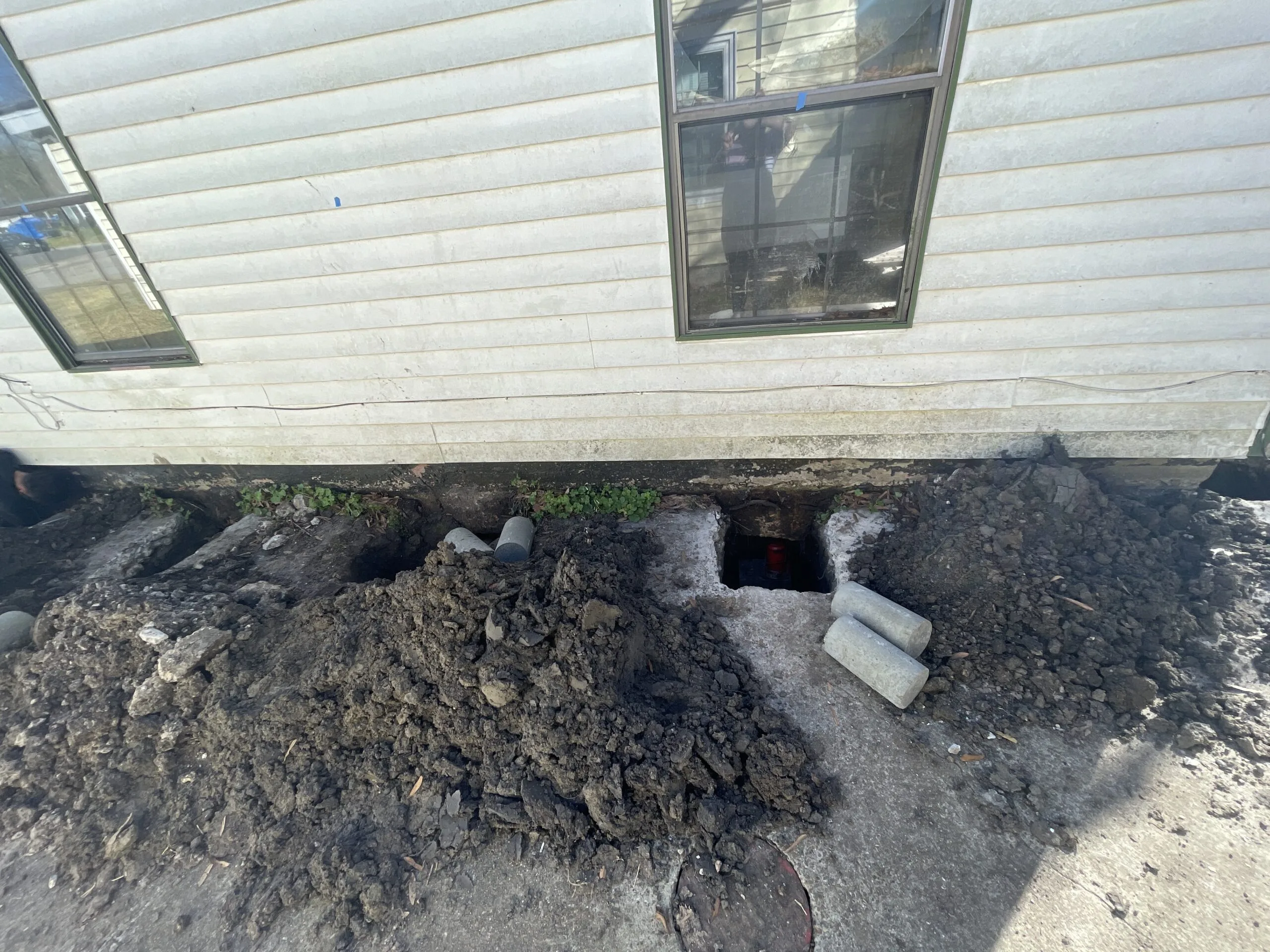 Foundation excavations and concrete pilings beside a raised house