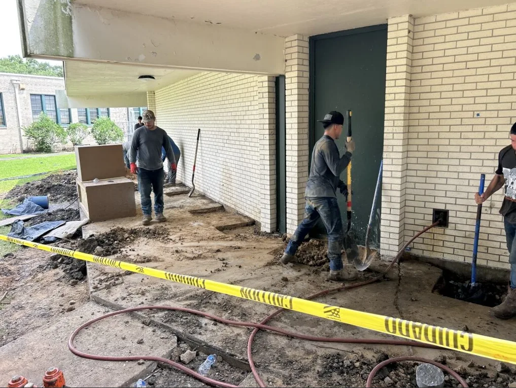 Workers repairing a commercial foundation under a covered area